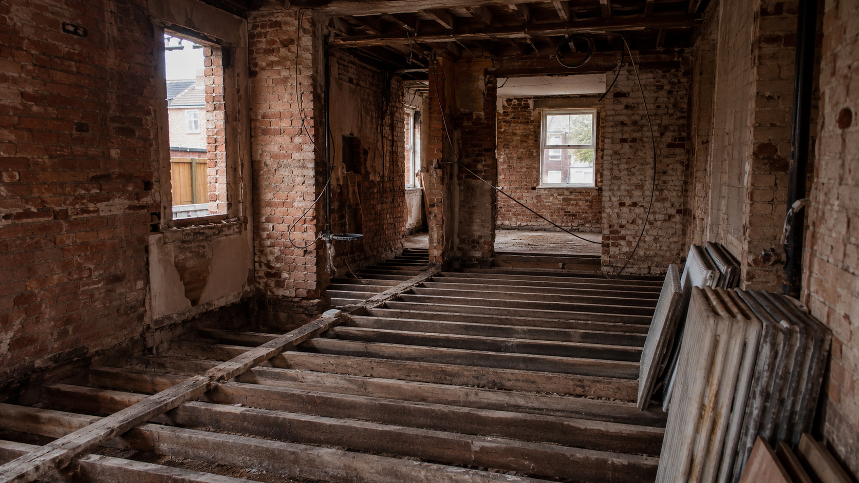 Gutted UK house mid-renovation with exposed walls and floor joists